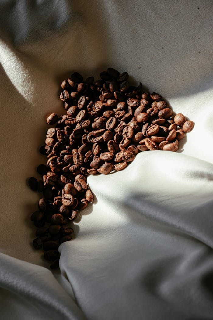 A visually striking close-up of coffee beans scattered on white cloth, showcasing rich textures.